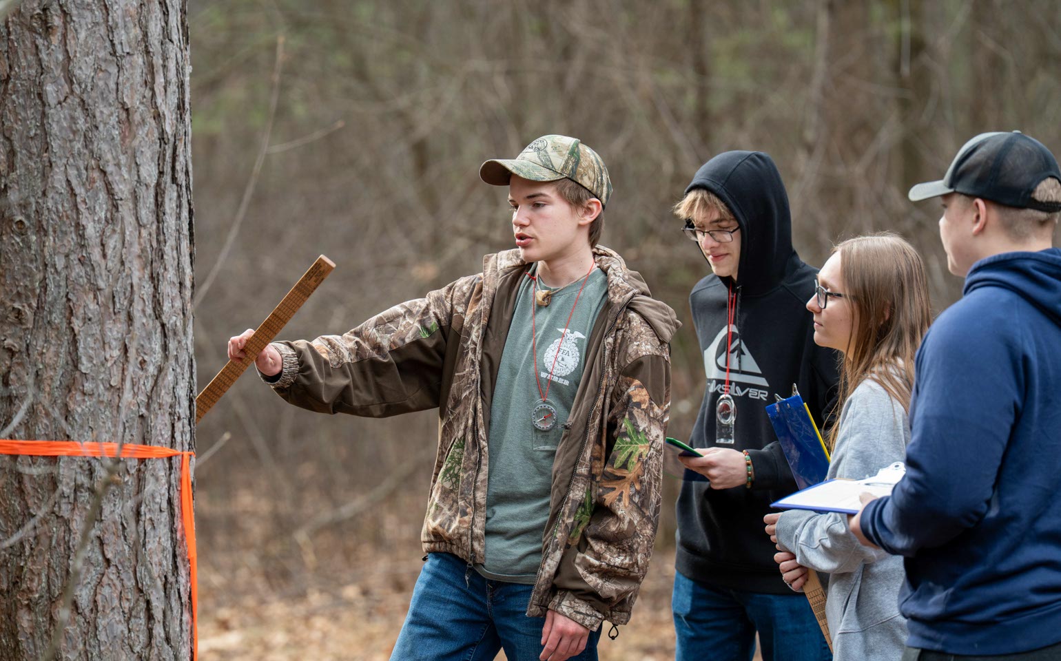 FFA students doing hands-on work with trees in the woods.