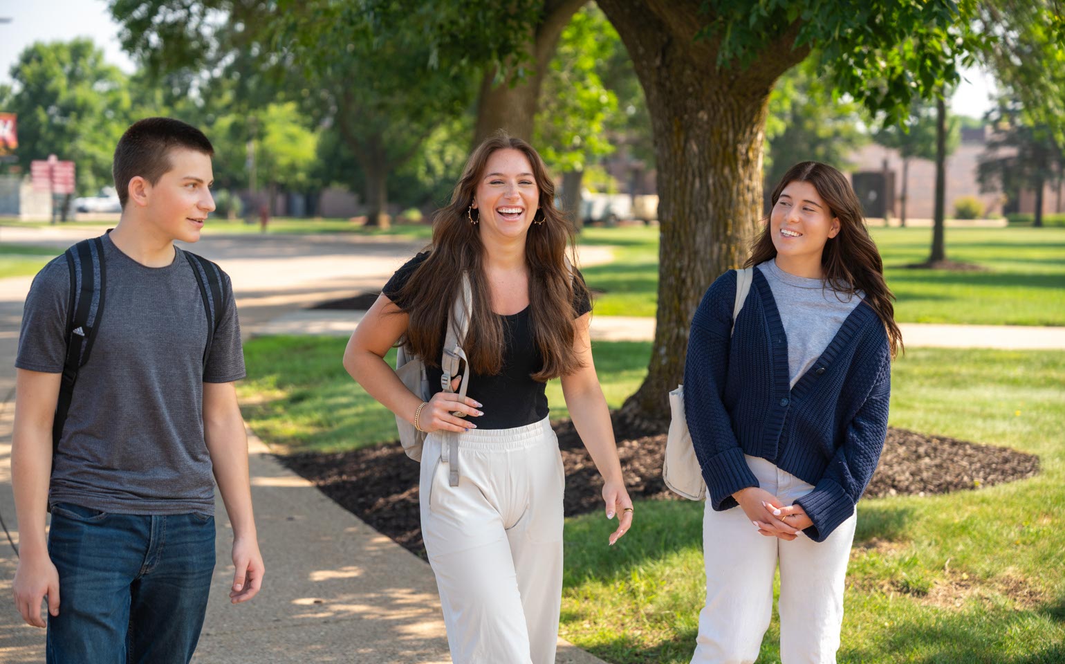 Three students with backpacks talk and laugh while walking together on Mid-State’s Wisconsin Rapids Campus.